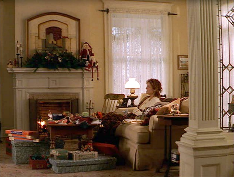 Susan Sarandon sitting on living room sofa beside the fire