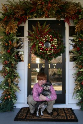 front porch with wreath and boy holding dog