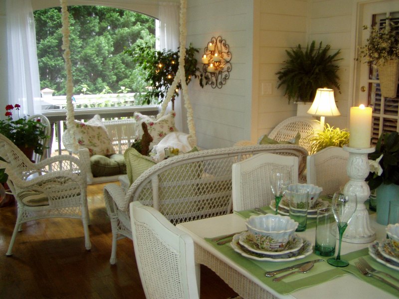 screened porch with porch swing and dining table with wicker chairs