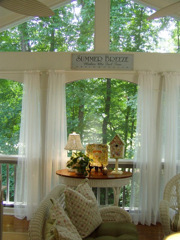 screened porch with curtains and sign that says Summer Breeze