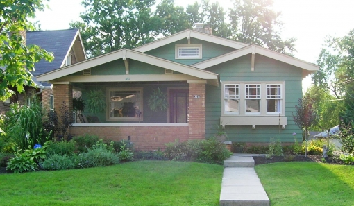 green bungalow with red brick porch