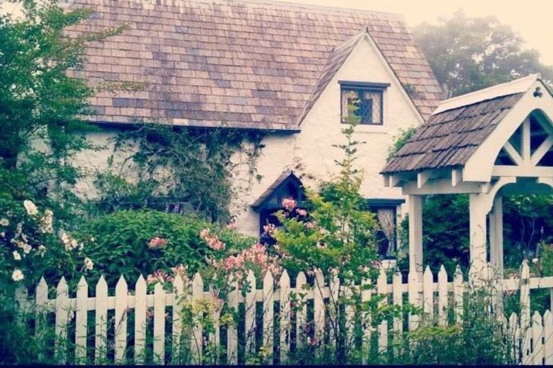 front of cottage with roses and white picket fence