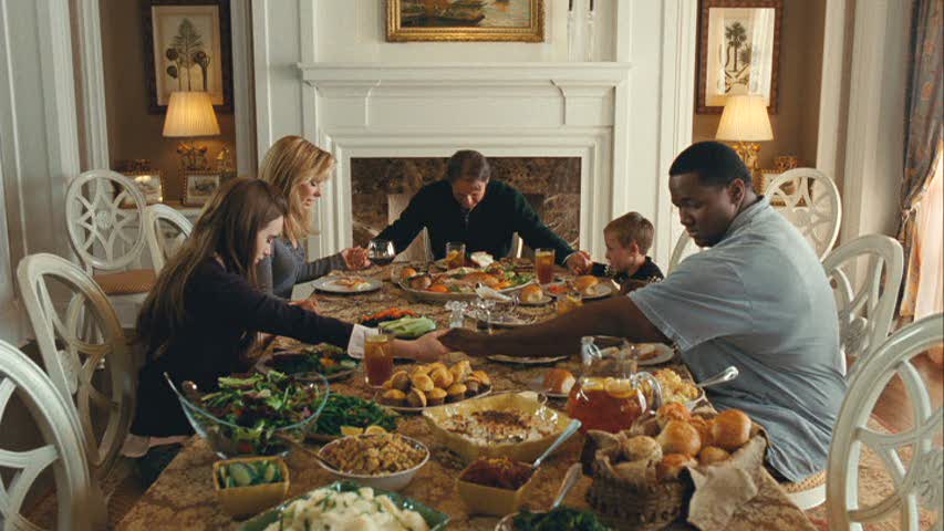 family praying before dinner in the dining room in The Blind Side movie house