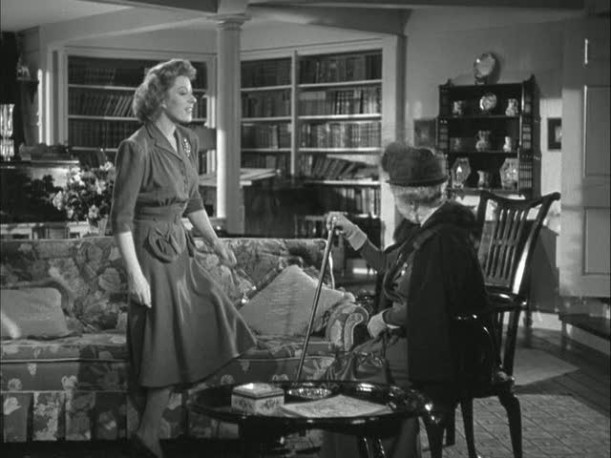 Mrs. Miniver standing in the living room by the sofa