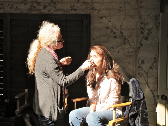 fixing an actress\'s makeup during filming