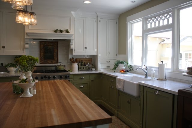 A kitchen with green lower cabinets and white uppers