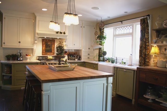 A kitchen with green lower cabinets and white uppers