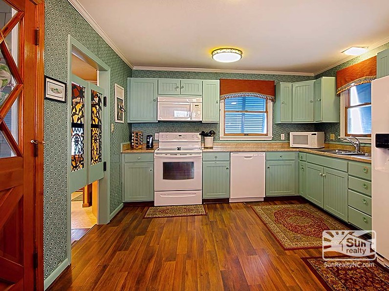 A kitchen with a wooden floor and painted cabinets after remodel