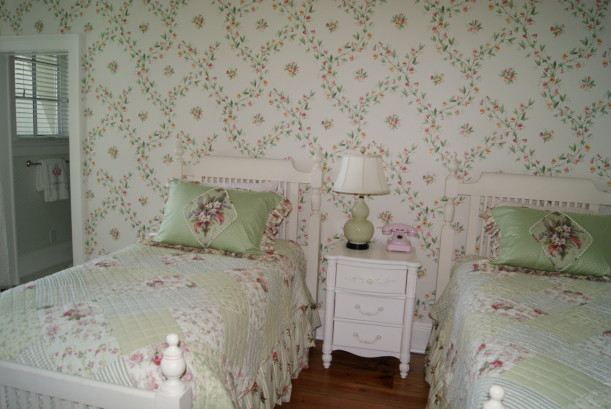 A bedroom with pink and green wallpaper