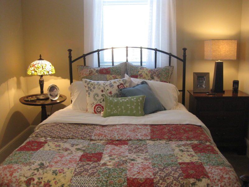 A bed with an iron headboard and quilt