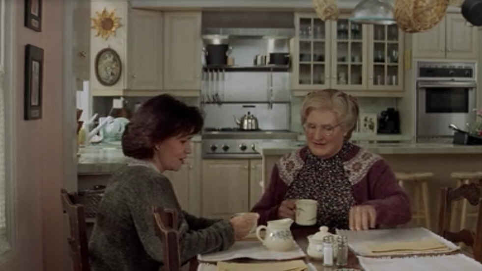 two people sitting at a table in a kitchen