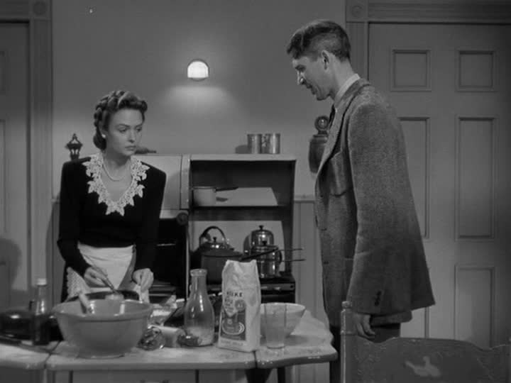 Mary and George Bailey standing in their kitchen while she bakes