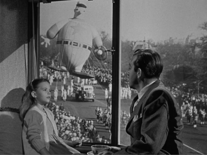 Susan watches the parade from John Payne\'s apartment