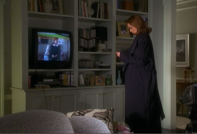 Elizabeth Perkins standing in front of TV in apartment