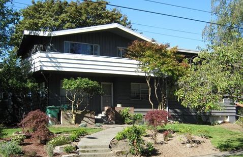 A house with bushes in front of a building before remodel