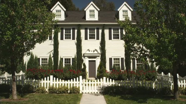 front exterior of Hanna\'s white house with black shutters and picket fence