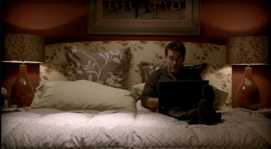 Julia\'s husband working on his laptop in the bedroom