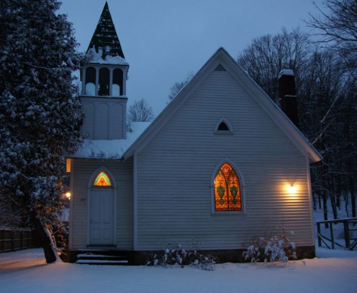 the converted church covered in snow at night with lights