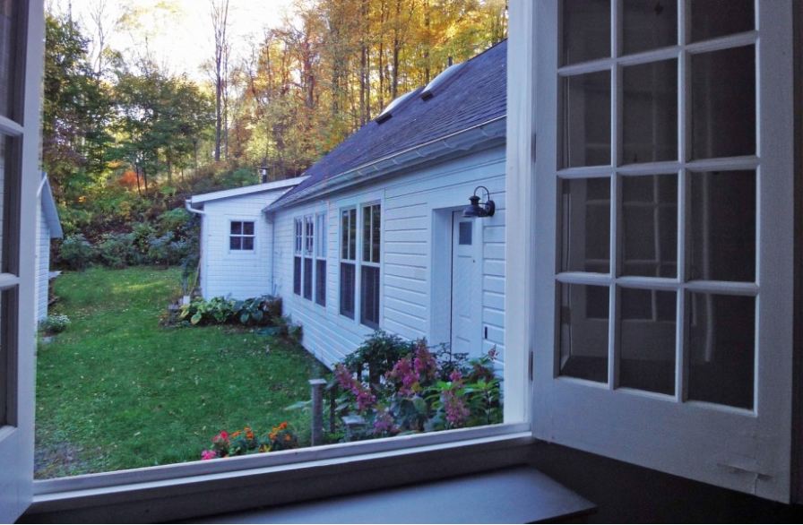 view from open window of side of the house and flower bed