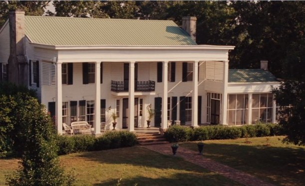 front exterior of white house with pillars and black shutters