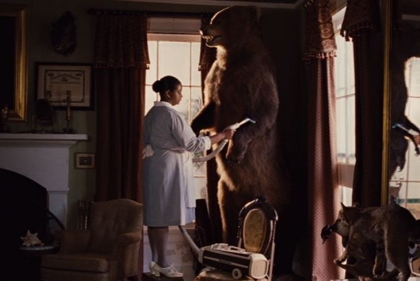 Minnie vacuuming the large stuffed bear in corner of study