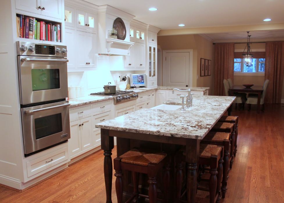 A kitchen with a stove top oven sitting inside of a wooden floor