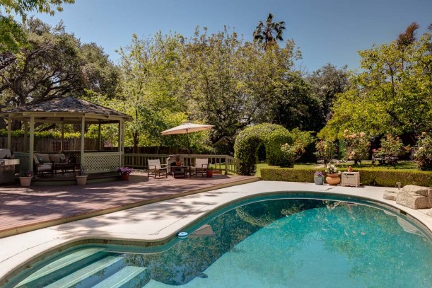 pool behind house with gazebo to side