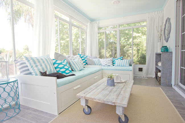 A sunroom with white curtains and sectional sofa