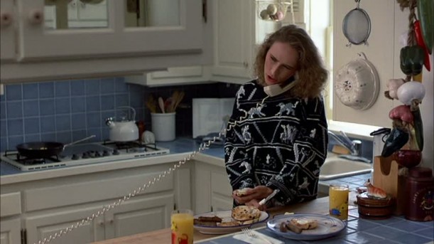 mother preparing food while talking on phone in kitchen