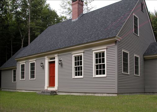 front exterior of cape style home with red door and gray siding