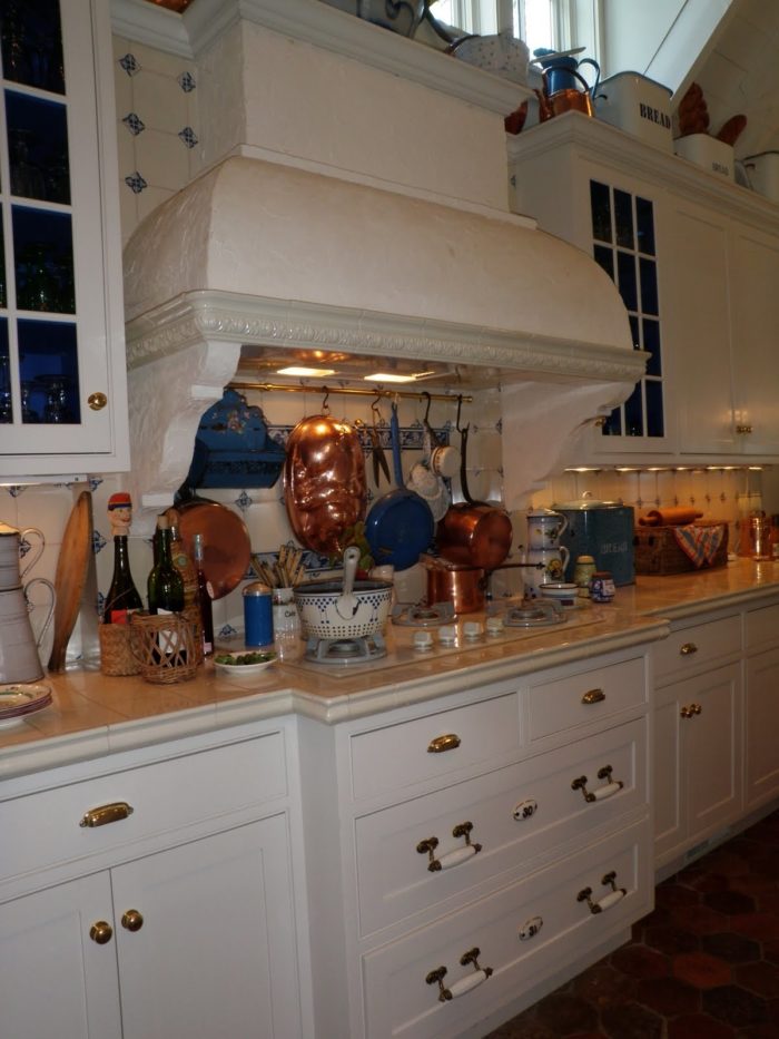 A kitchen with center stove and large vent hood