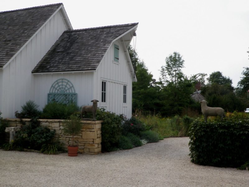 exterior of French Country style farmhouse with stone wall and lamb statue