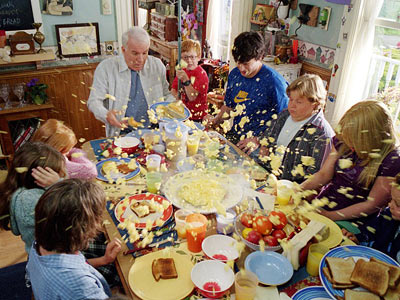 A group of people sitting at a table full of food in Cheaper By the Dozen