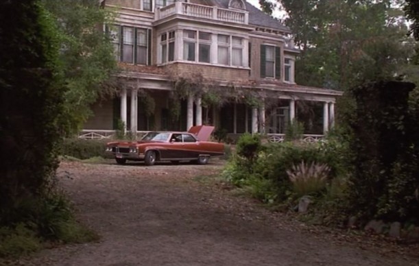 dirt road leading to mansion with car parked in front