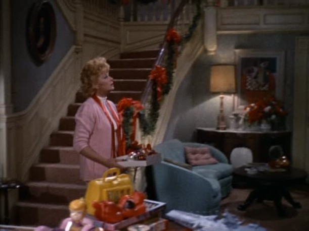 Lucille Ball standing at base of staircase