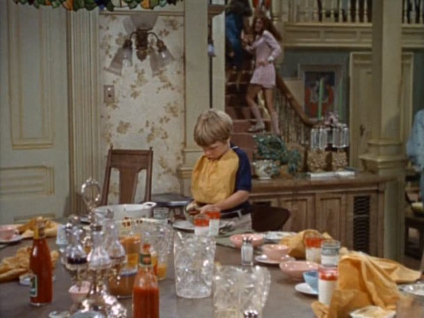 child standing at messy dining room table