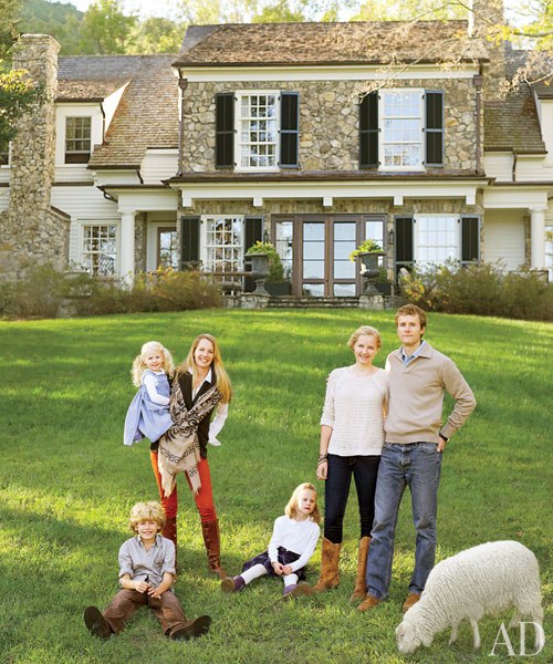 A group of people standing in front of a building with a grassy field