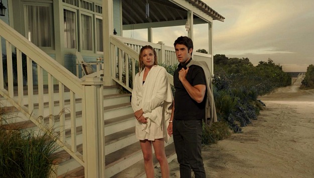 Emily and Daniel standing at the base of the steps of her beach house