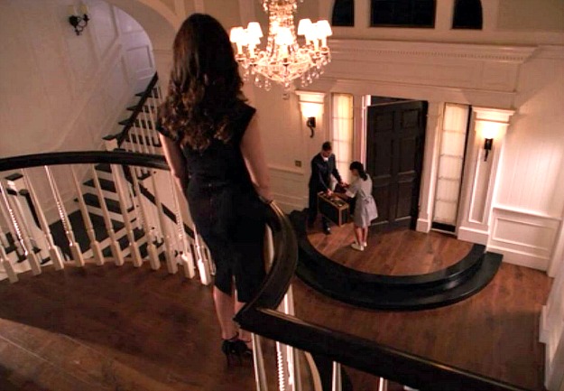 Victoria Grayson standing at top of stairs overlooking entry hall