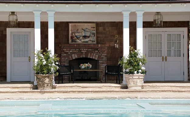 A fireplace in the covered porch of the pool house