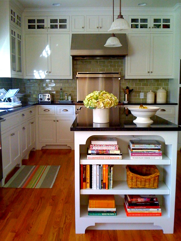 kitchen with green subway tile, white cabinets and black countertops