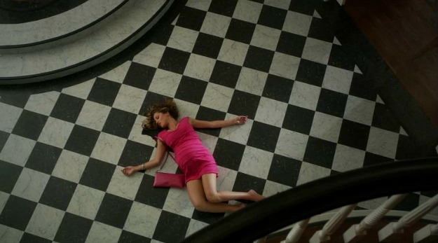 A person lying on a black and white checkerboard tiled floor