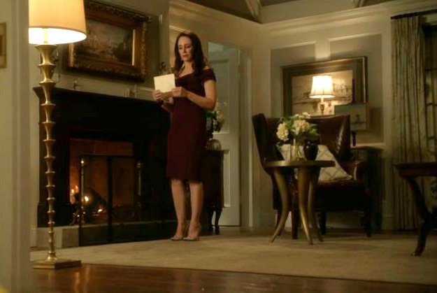 Victoria standing beside fireplace