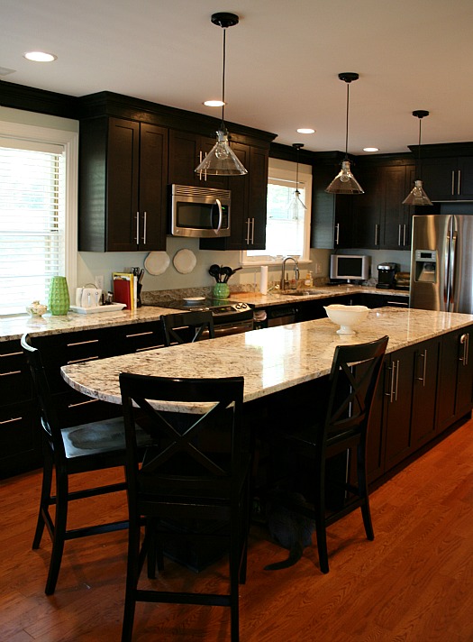 A kitchen with large marble island and black cabinets