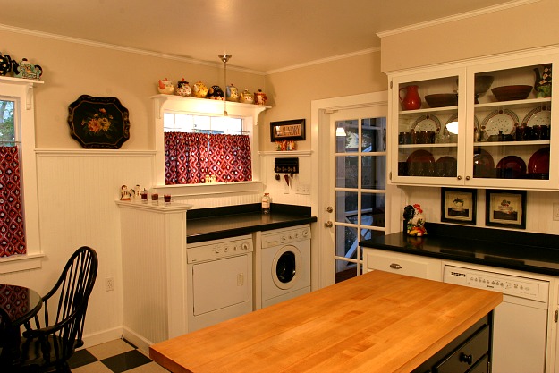 A kitchen with washer and dryer in corner of room after remodel