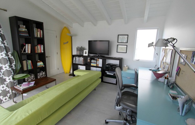 A living room with yellow surfboard in corner