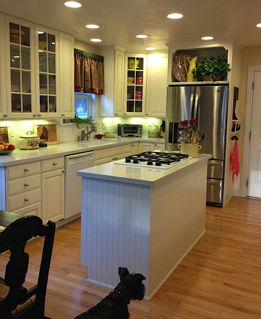 A kitchen with an island in the middle of a hard wood floor