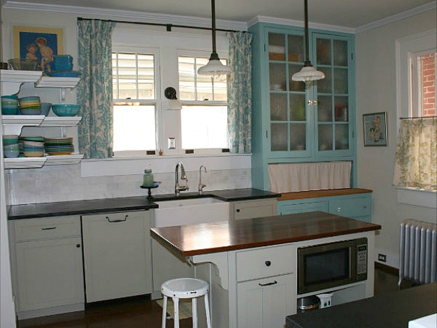 A kitchen with turquoise cabinets and curtains