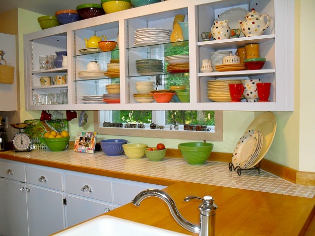 A kitchen with open cabinets filled with colorful ceramic pieces