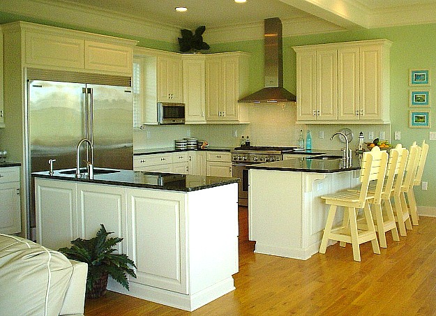 a kitchen with white cabinets and black granite countertops